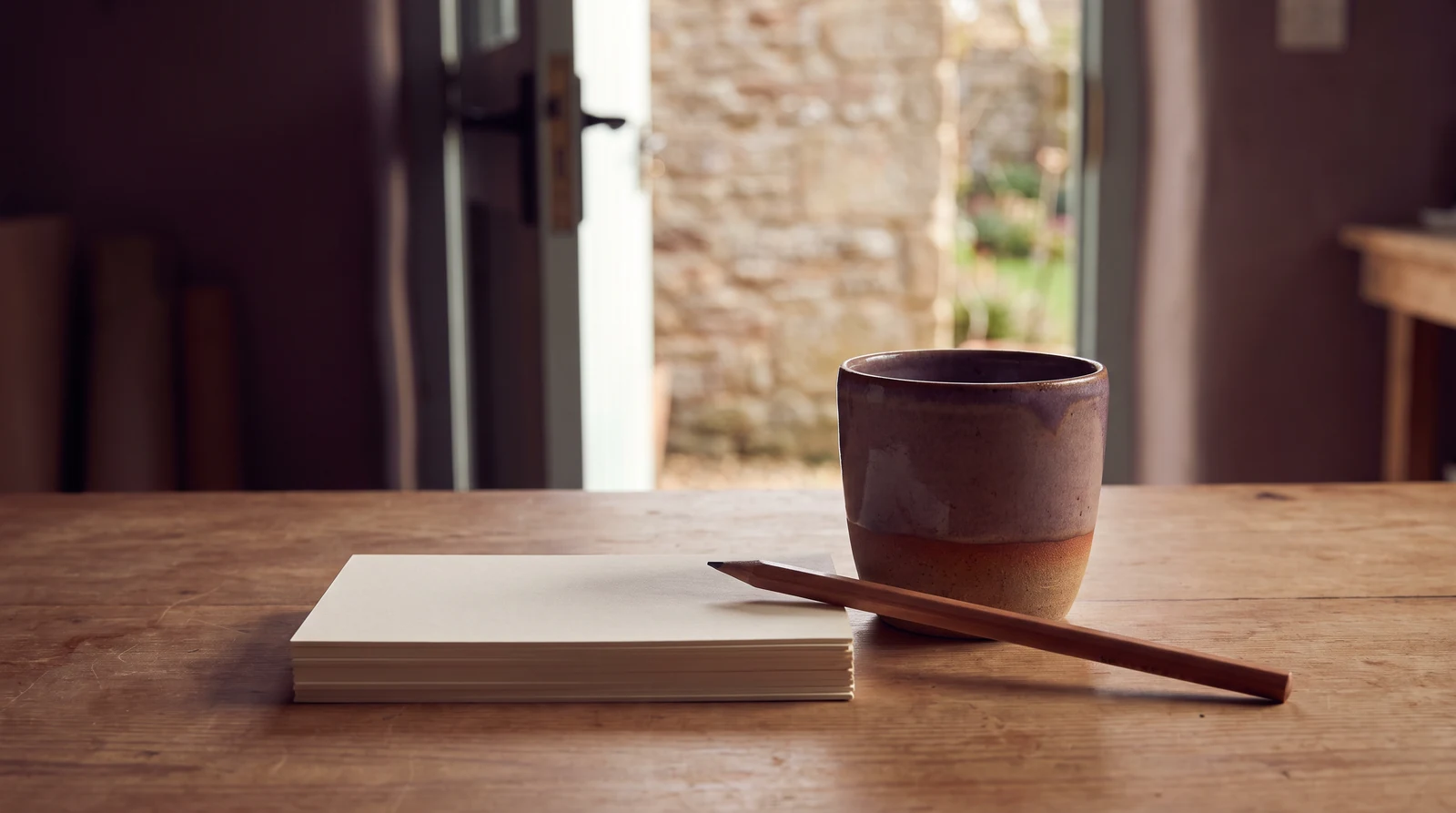 Notebook, pencil and cup on a wooden table